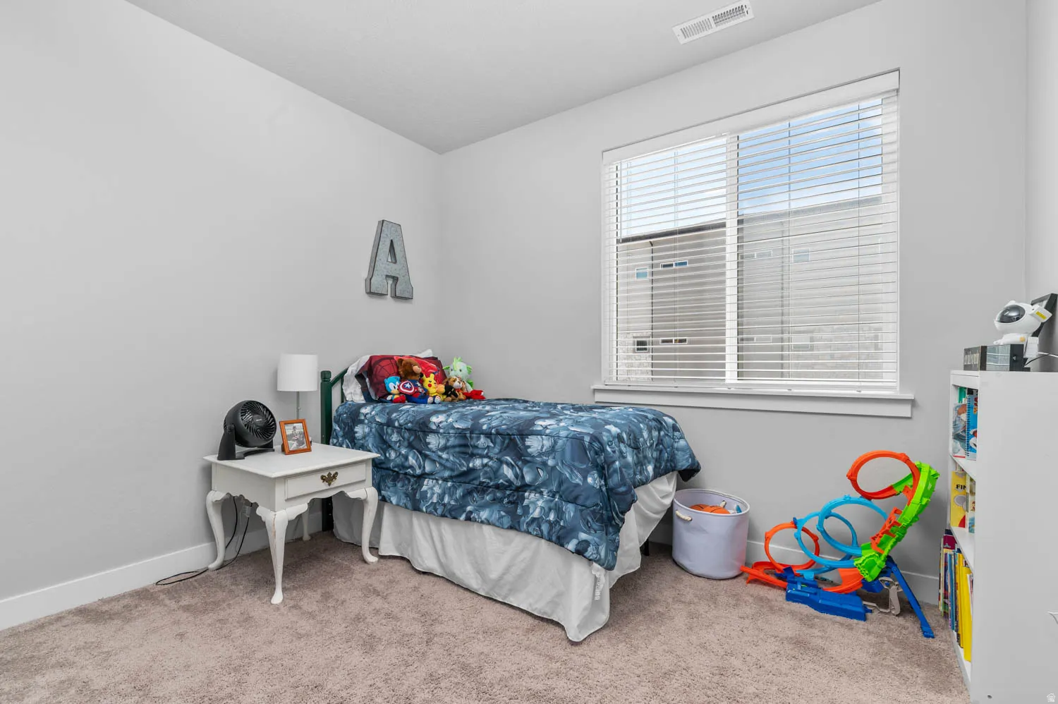 Carpeted room featuring a large window with blinds, white trim, and a ceiling vent