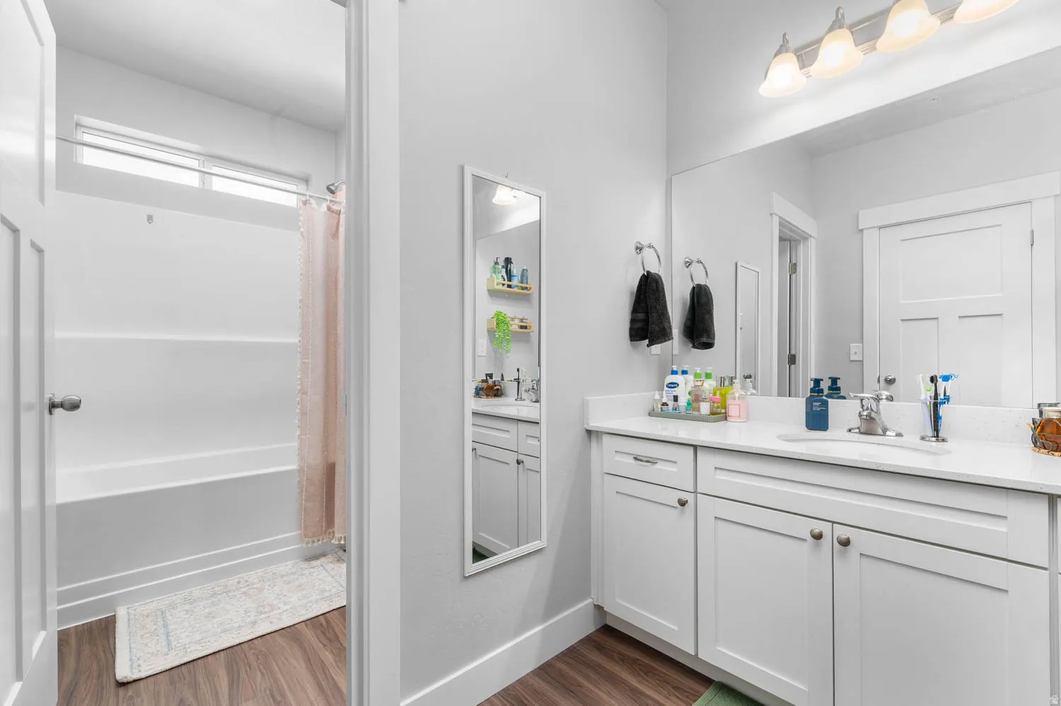 Modern master bathroom featuring a double vanity with white cabinetry, integrated sinks, and a large mirror