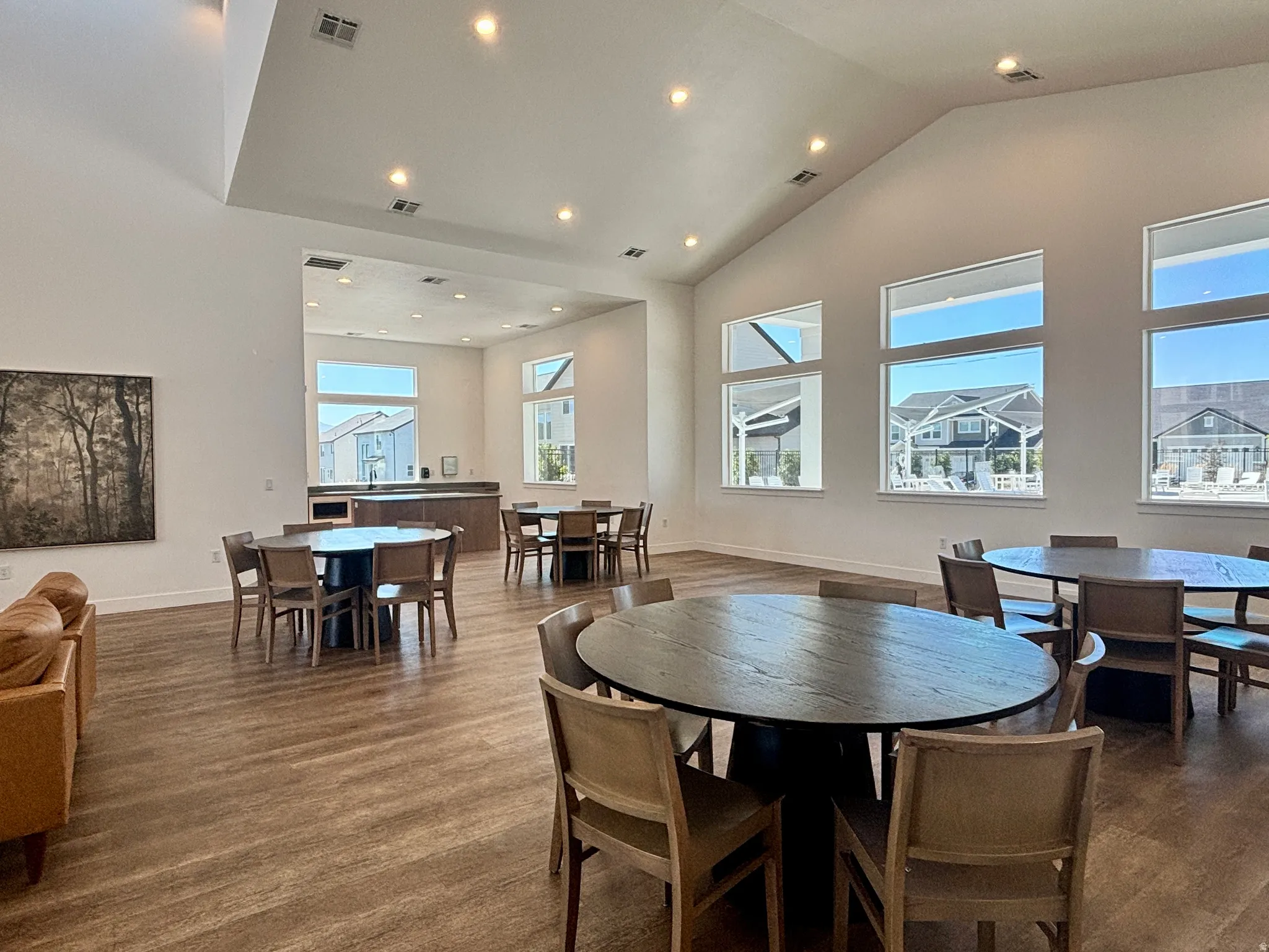 CLUBHOUSE INTERIOR Spacious common area featuring vaulted ceilings, recessed lighting, wood-finish flooring, and multiple large windows