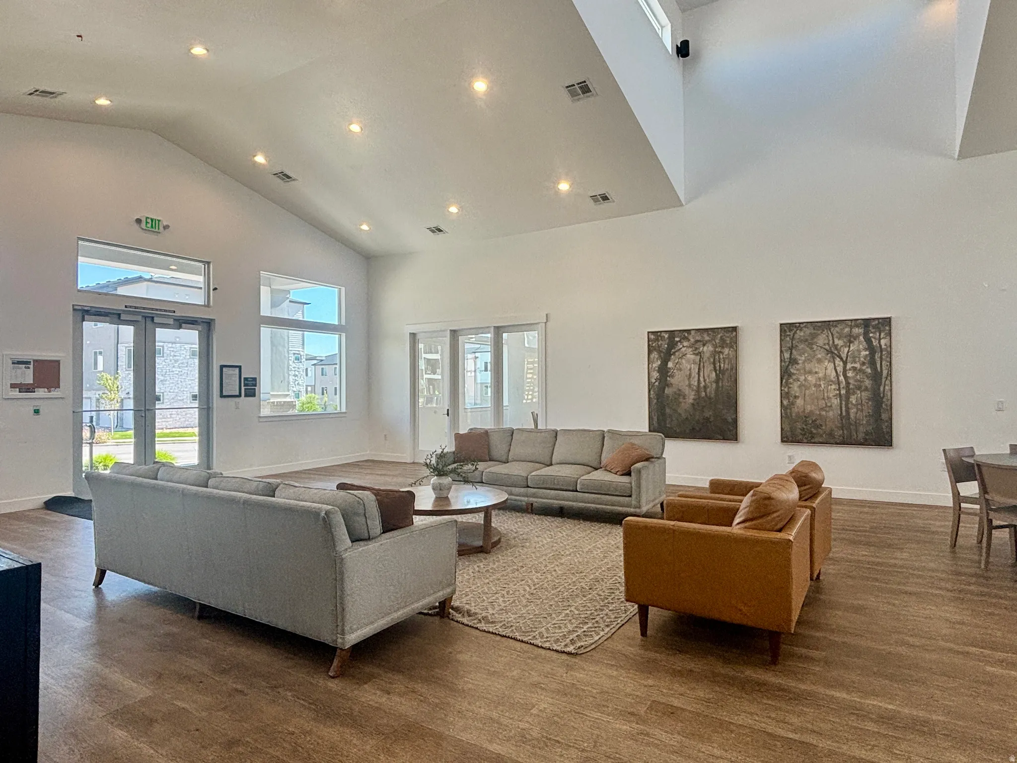 CLUBHOUSE INTERIOR Spacious common area featuring vaulted ceilings, recessed lighting, wood-finish flooring, and abundant natural light from multiple windows