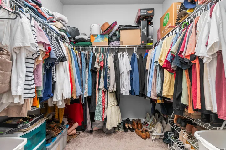 Walk-in closet featuring wire shelving, multiple hanging rods, and carpet flooring
