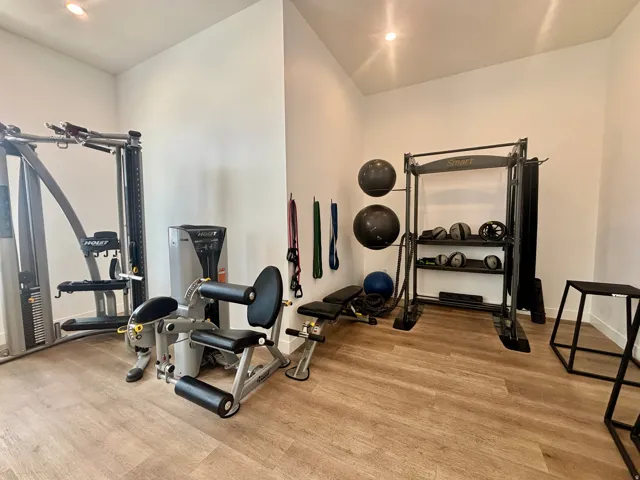 Dedicated fitness room featuring wood-finish flooring, recessed lighting, and bright white walls
