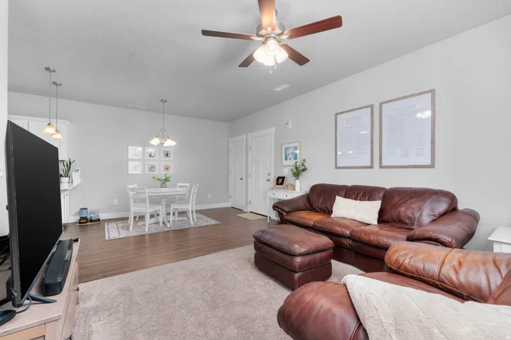 Living room with neutral wall paint, overhead ceiling fan, and carpeted flooring