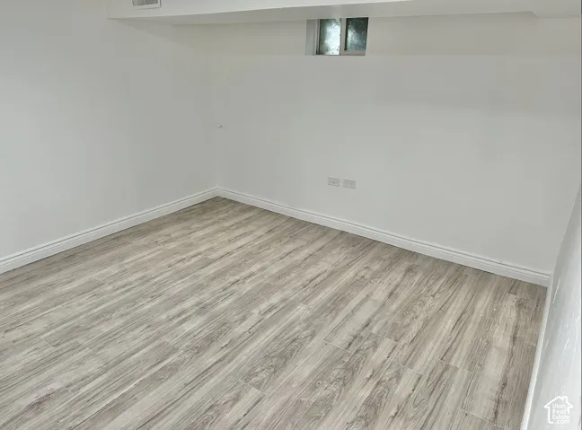 Room featuring light wood-finish flooring, crisp white walls, and a recessed window