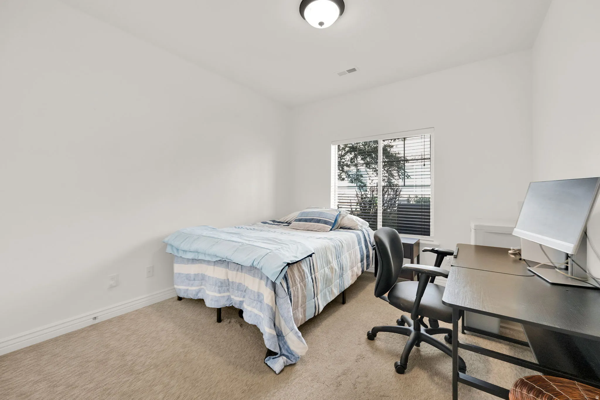 Bright room featuring a large window with horizontal blinds, neutral carpeting, and a flush mount ceiling light fixture