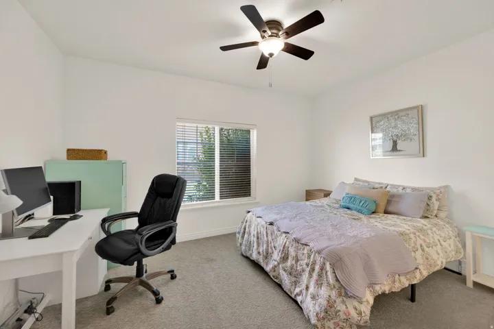 Carpeted room featuring a ceiling fan with light fixture, a window with blinds, and white painted walls