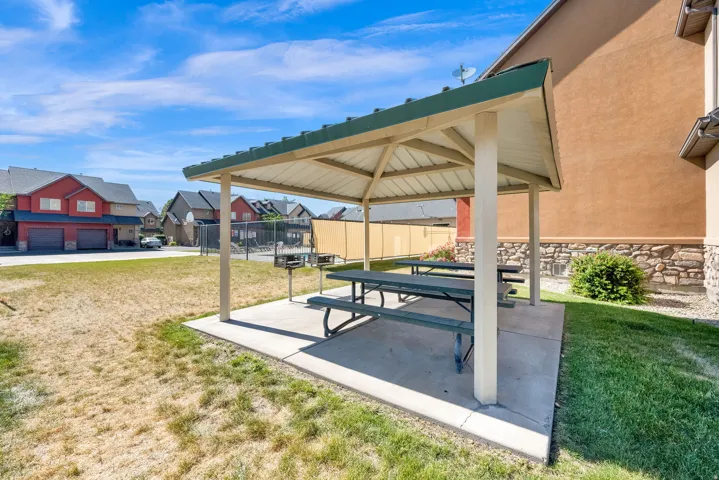 Community picnic area featuring a covered pavilion with metal roof, concrete pad, and two built-in picnic tables
