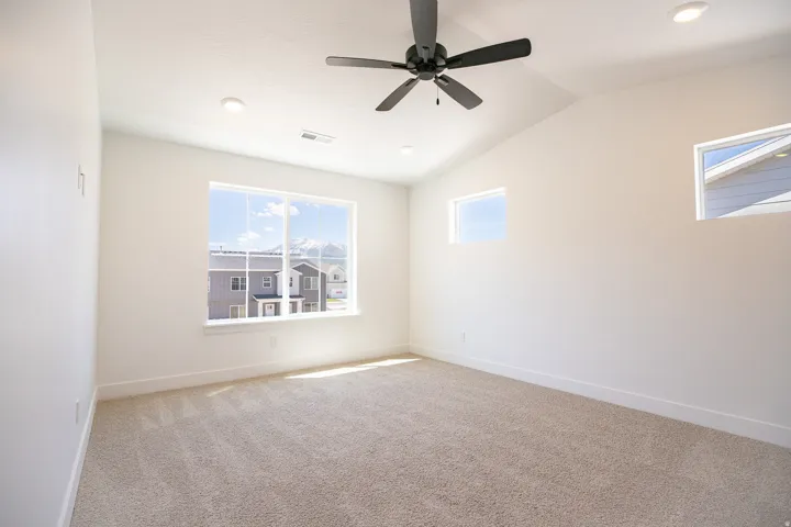 Primary bedroom with vaulted ceilings and a ceiling fan