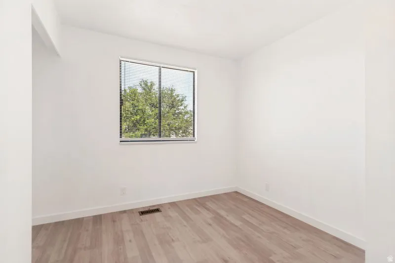 Bright room featuring a window with horizontal blinds, offering treetop scenery