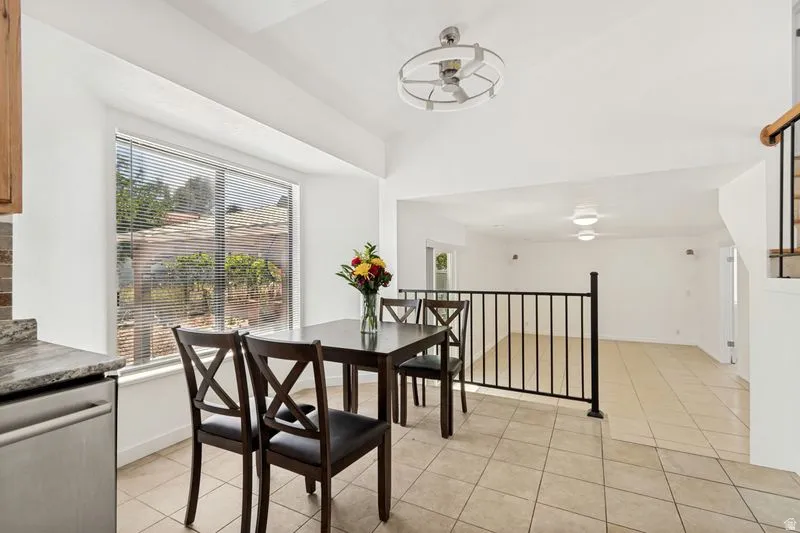 Kitchen area featuring a large window, tiled flooring, granite-look countertop, and a stainless steel dishwasher
