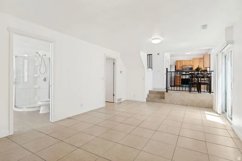 Tiled flooring throughout the main living area, with a full bathroom featuring a glass-enclosed shower
