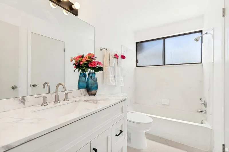 Bathroom featuring a white vanity with a marble-patterned countertop and an integrated sink, brushed nickel faucet, and a large wall-mounted mirror