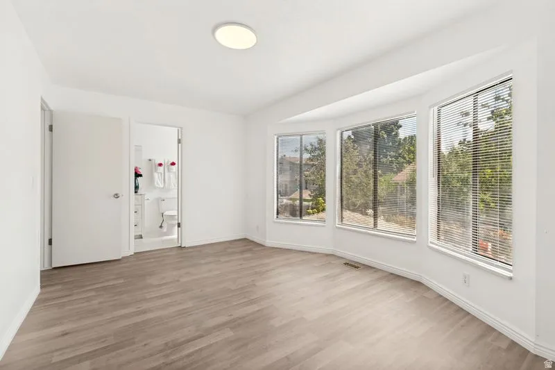 Bay window with multiple large panes, light-colored wood-finish flooring, white walls, and a visible ceiling light fixture