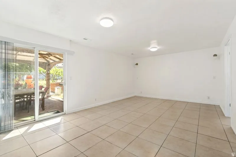 Spacious room featuring neutral tile flooring, white walls, and two ceiling-mounted light fixtures