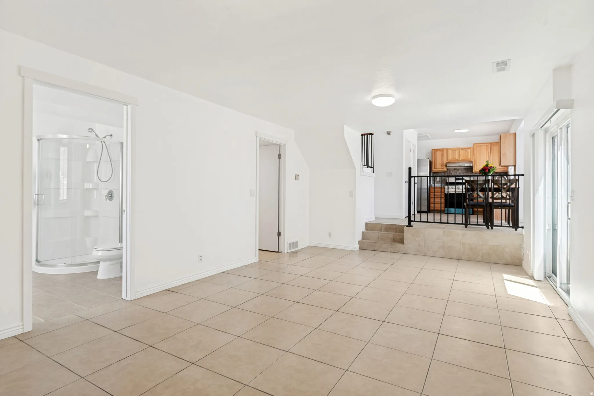 Open-concept living space featuring neutral tone tile flooring and white walls