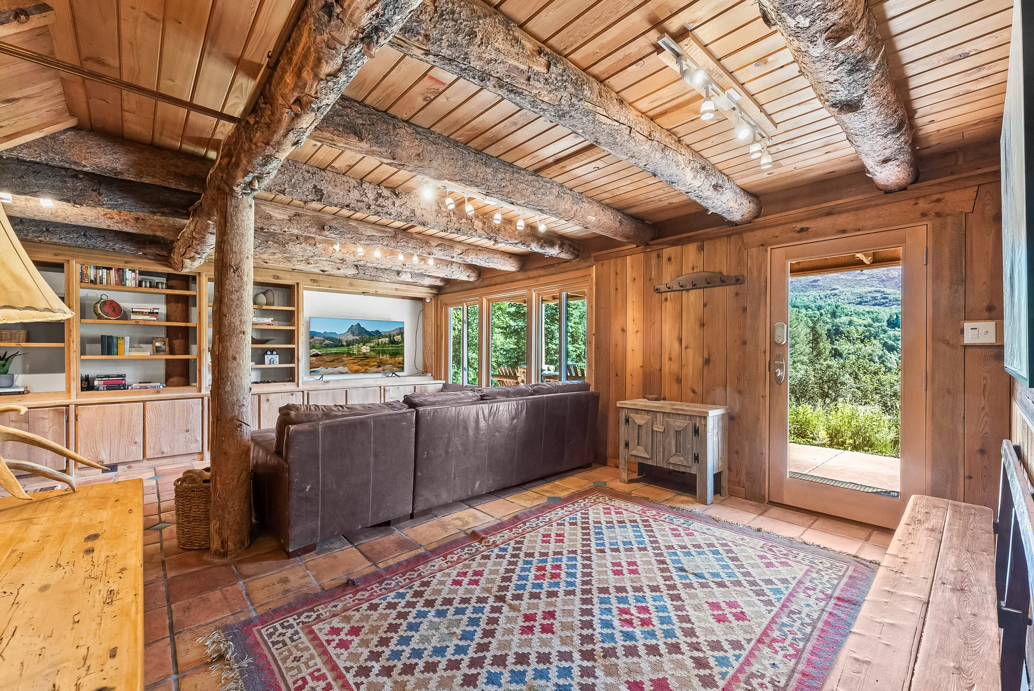 Living area featuring rustic wood beam ceilings, wood-finish walls, and terracotta tile flooring