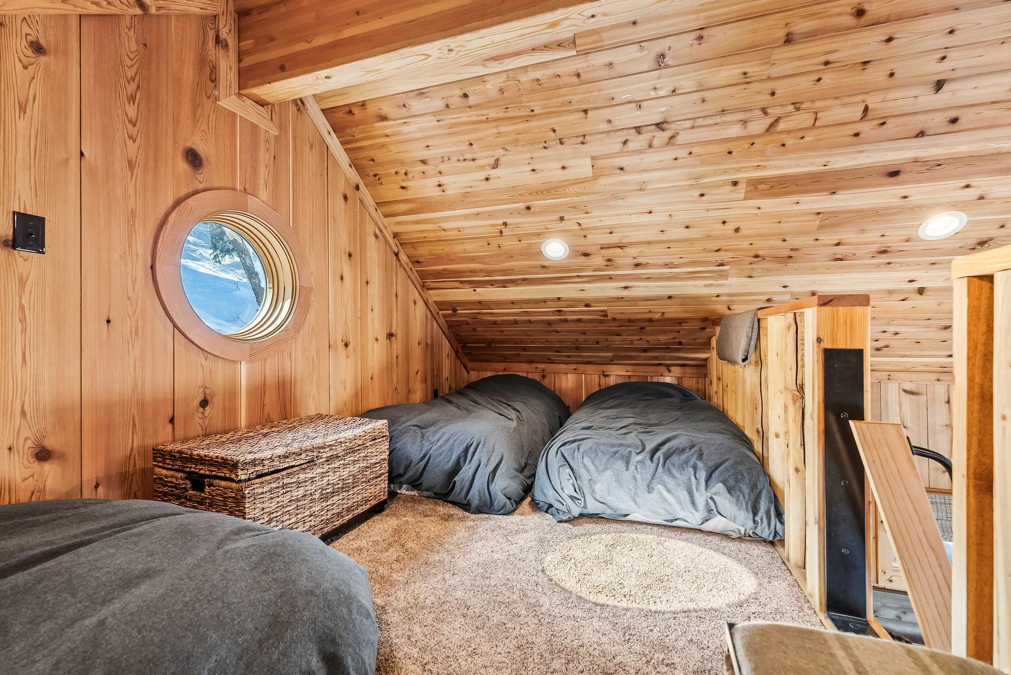 Wood paneling throughout, circular window feature, built-in wooden partition, recessed lighting, and carpeted flooring