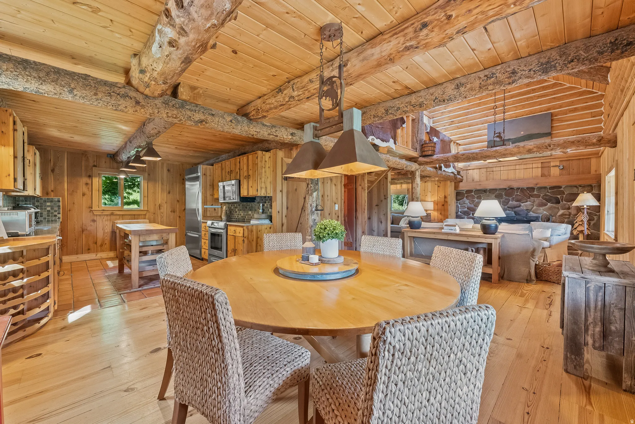 Open-concept living space featuring exposed log beams, wood-plank walls, and wood-finish flooring