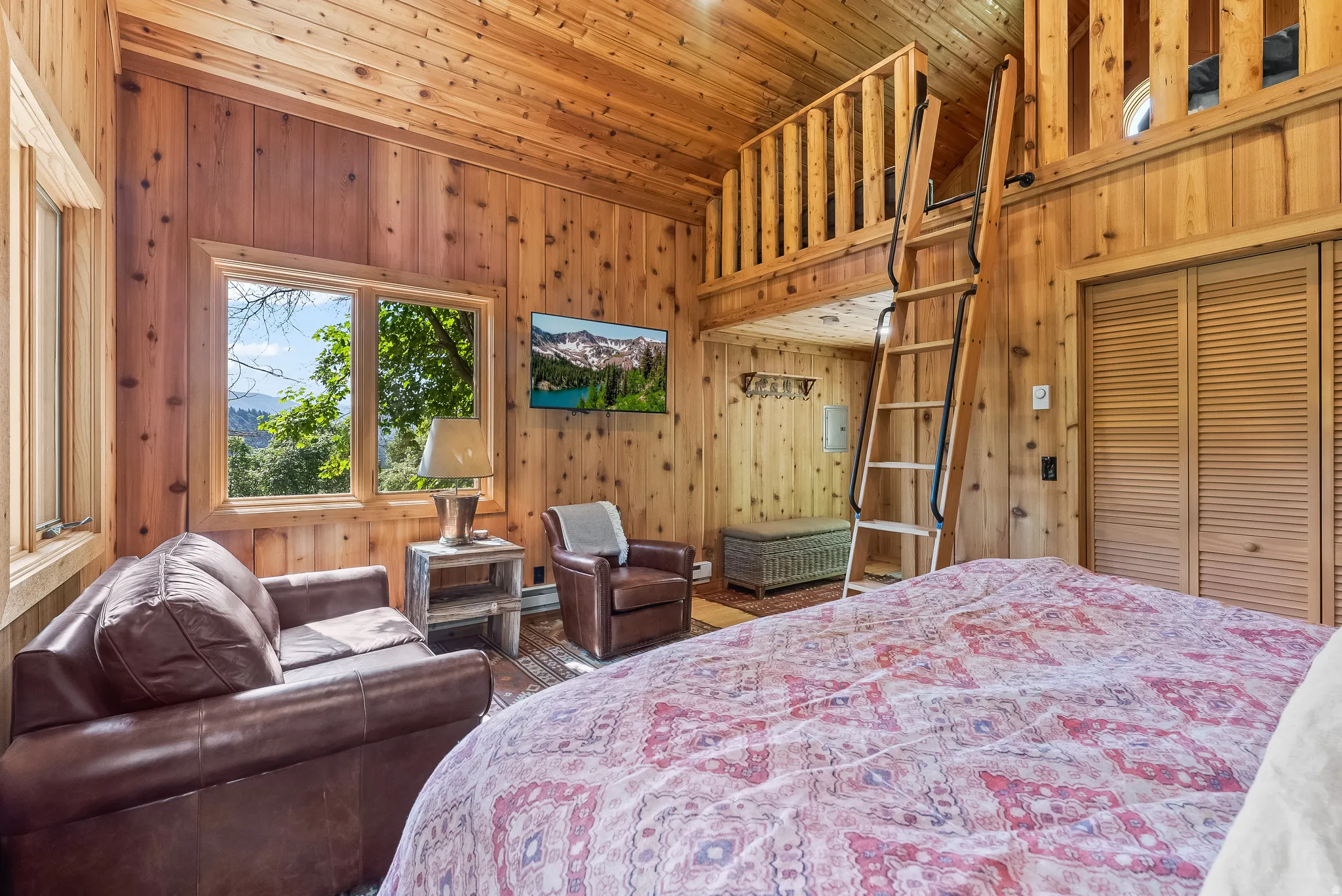 Interior featuring extensive wood paneling and wood-finish ceiling, multiple windows, a built-in loft with wood railing, and a wood ladder for access