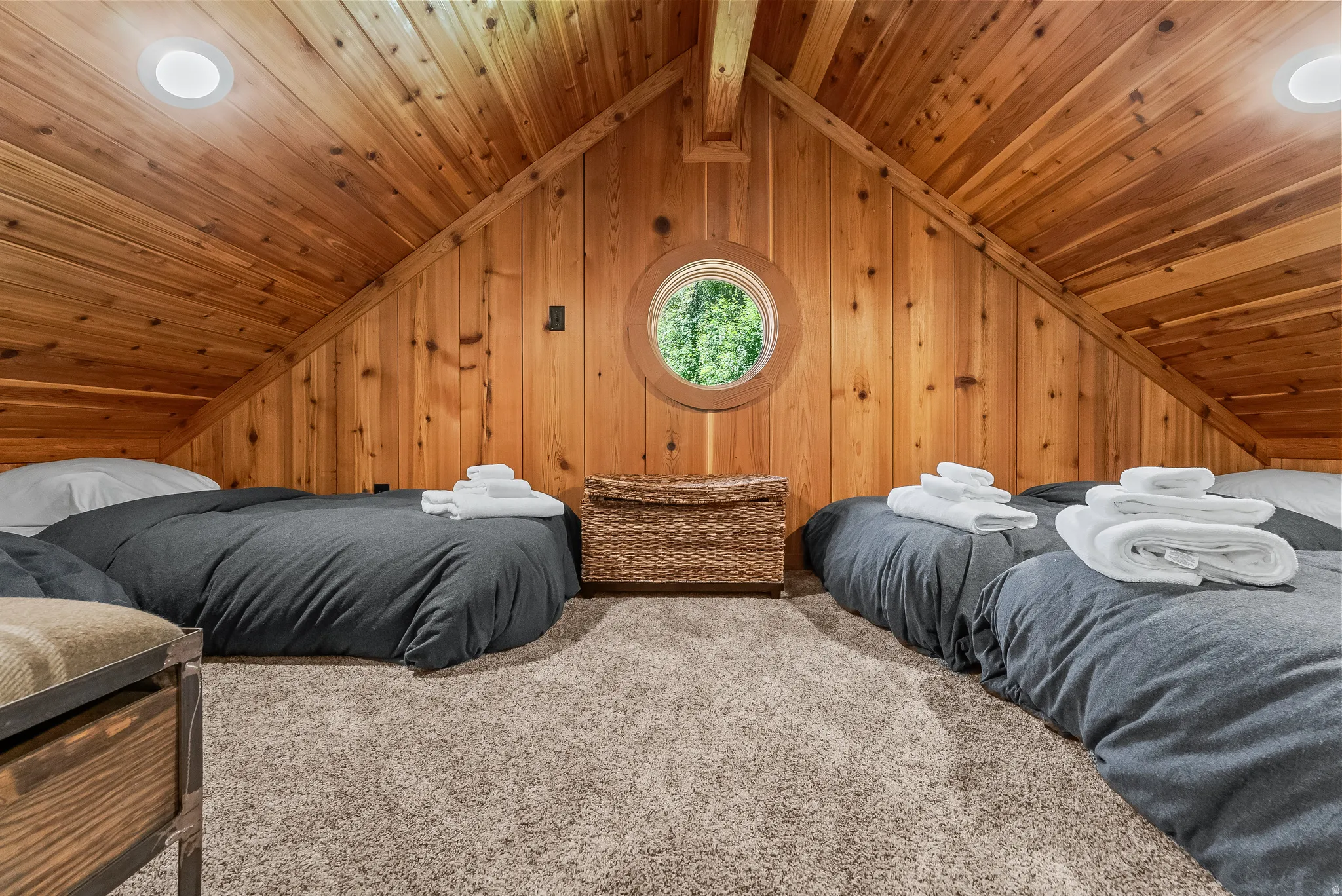 Loft space featuring warm wood paneling throughout, a circular window, recessed lighting, and soft gray carpeting