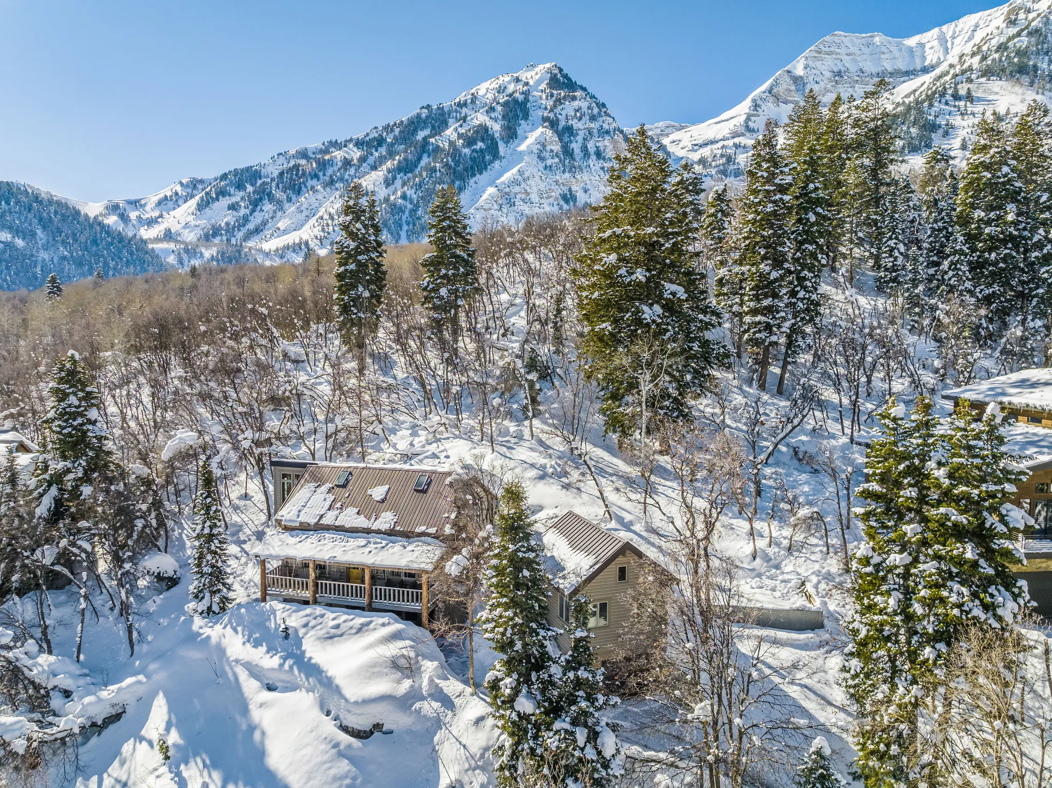 Mountain-side property featuring a multi-level structure with a covered porch and a metal roof