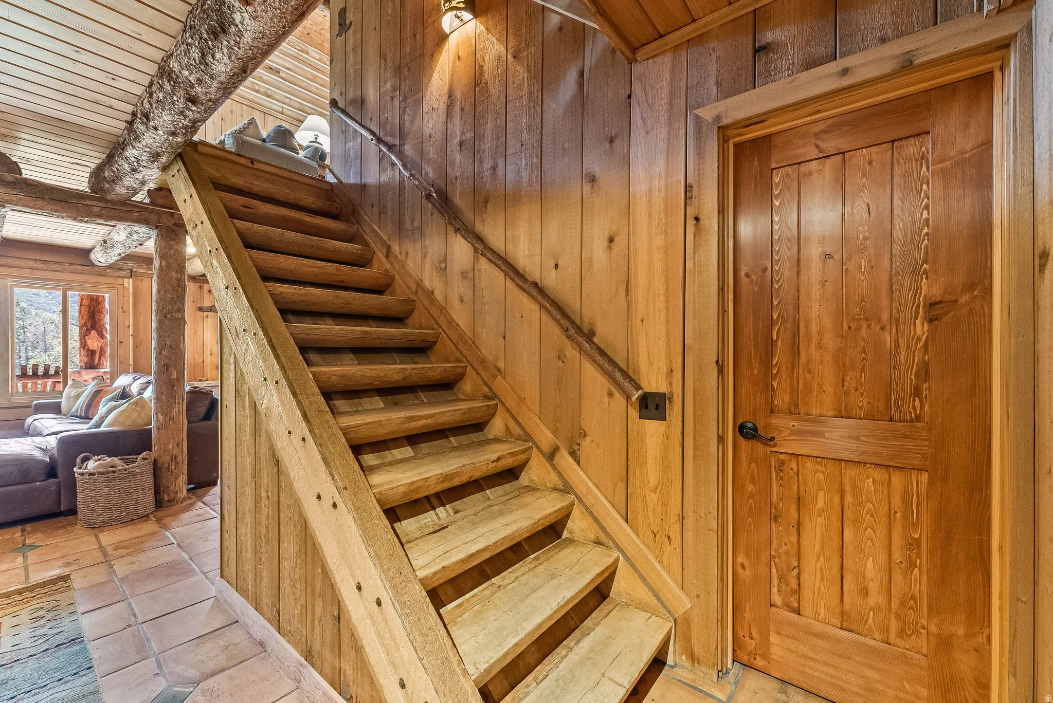 Rustic wood staircase featuring a log railing and exposed wood ceiling beams