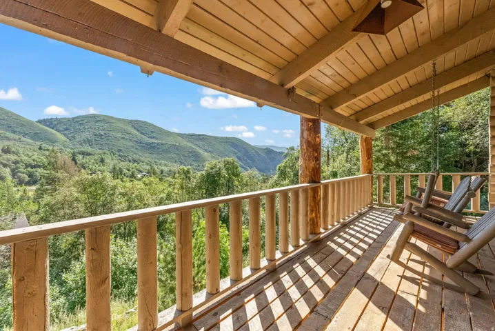 Expansive covered wood deck featuring natural wood railing and structural posts