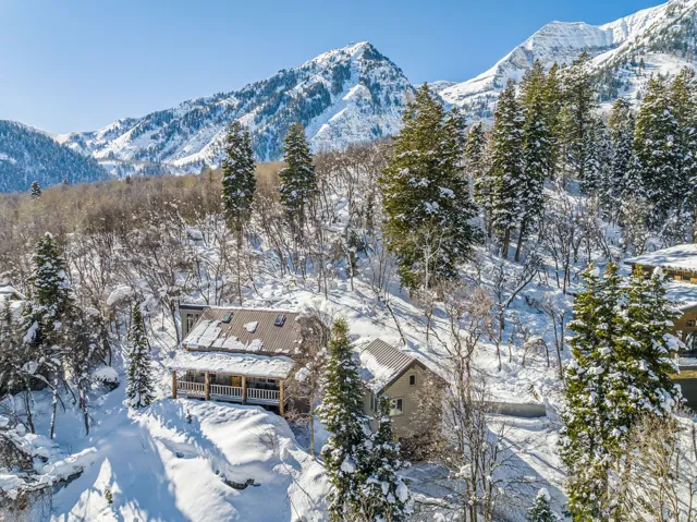 Mountain-side property featuring a multi-level structure with a covered porch and a metal roof