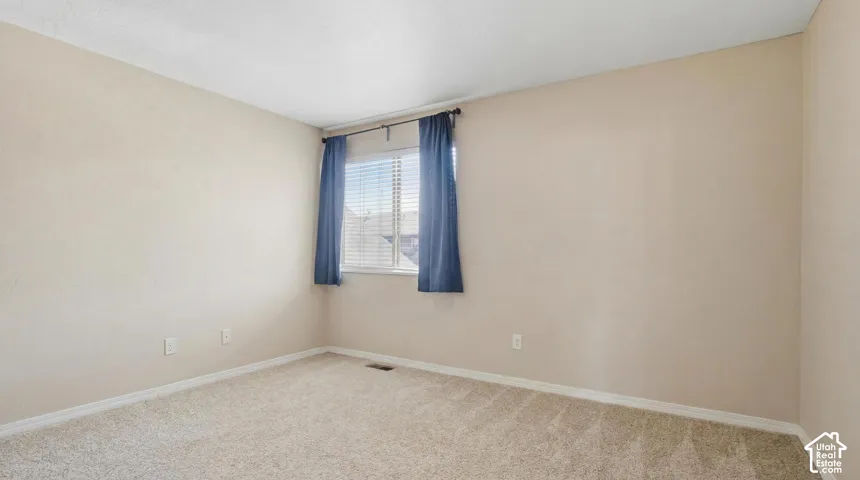 Carpeted room featuring a window with horizontal blinds, light-toned wall paint, and white baseboards