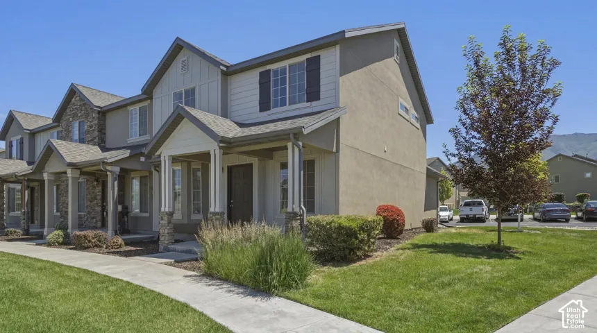 End-unit townhouse featuring a two-story design with a covered porch and stone accents