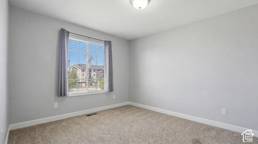 Neutral-toned wall finish, carpet flooring, and a window with horizontal blinds and drapery
