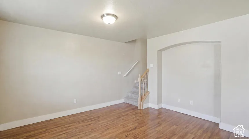 Living area featuring wood-finish flooring, light neutral wall tones, white baseboards, and a flush mount ceiling light