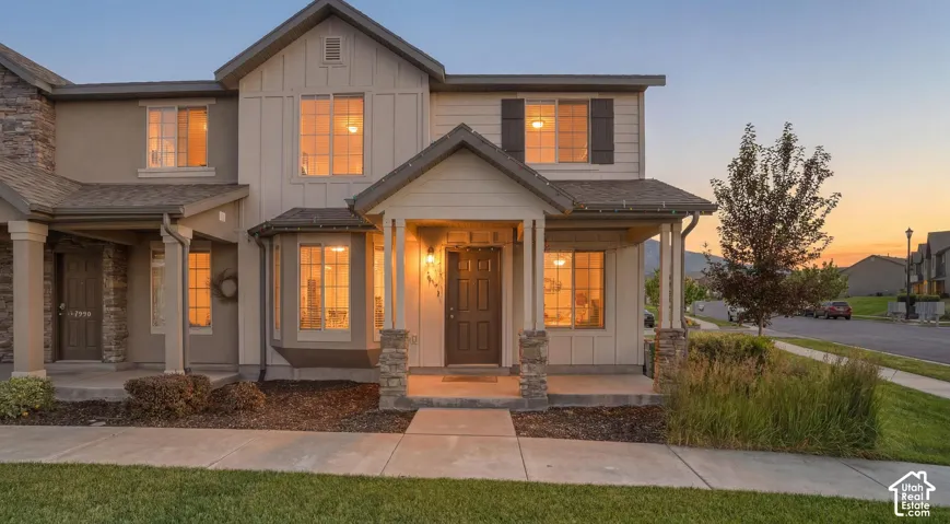 Contemporary dwelling featuring a covered front porch, stone column accents, and board and batten siding