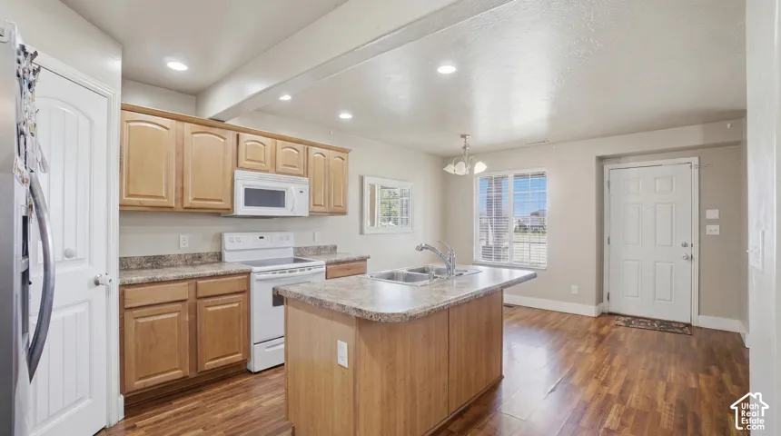 Open kitchen area featuring wood-finish flooring, light-toned cabinetry, and a central island with an integrated sink