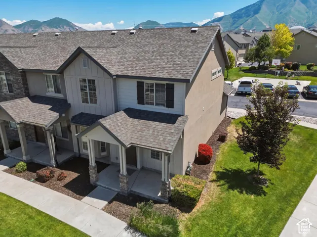 Townhome exterior featuring a neutral stucco and siding combination, covered entry porch, and an asphalt shingle roof