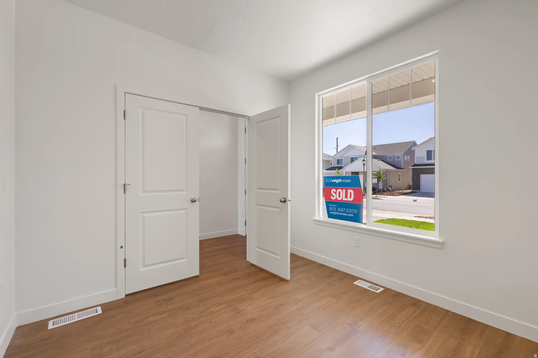 Bright room featuring wood-finish flooring, white walls, and a large window
