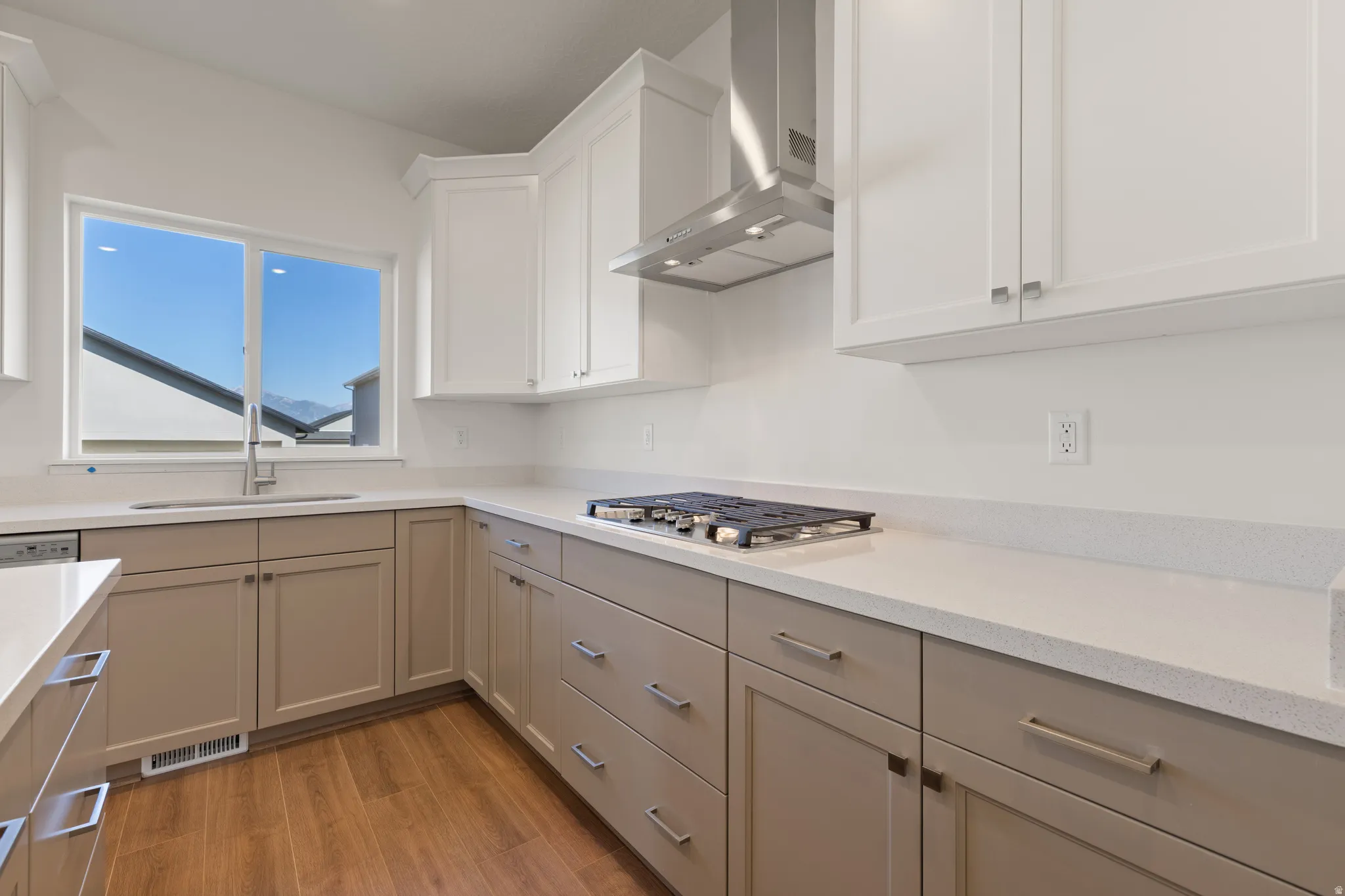 Contemporary kitchen featuring white upper cabinetry and taupe base cabinetry with stainless steel hardware