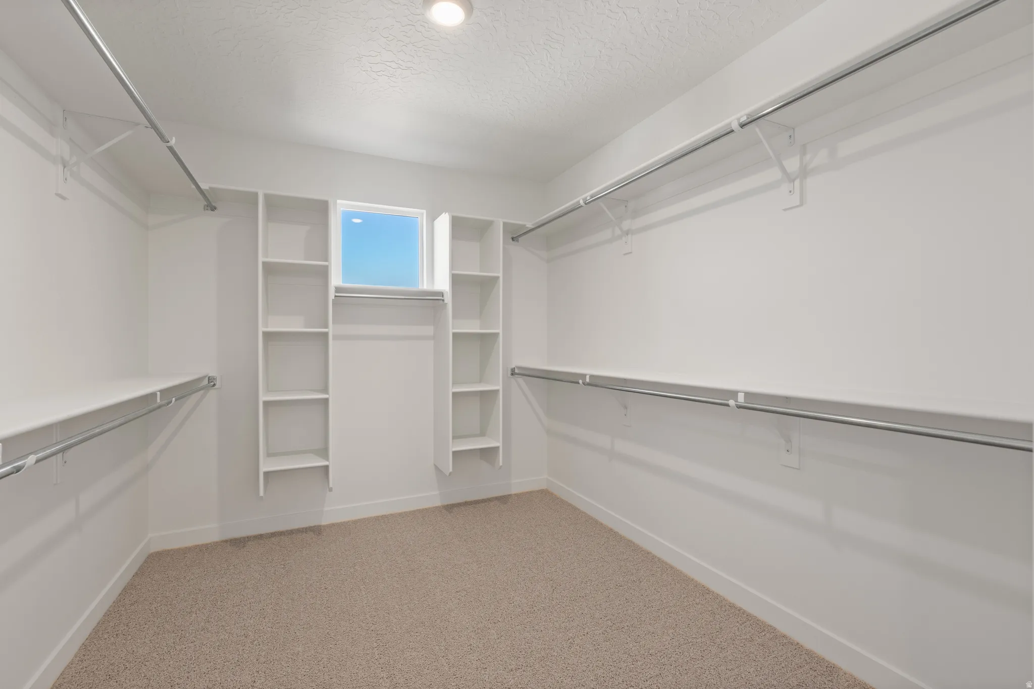 Walk-in closet featuring built-in shelving, hanging rods, and a window for natural light
