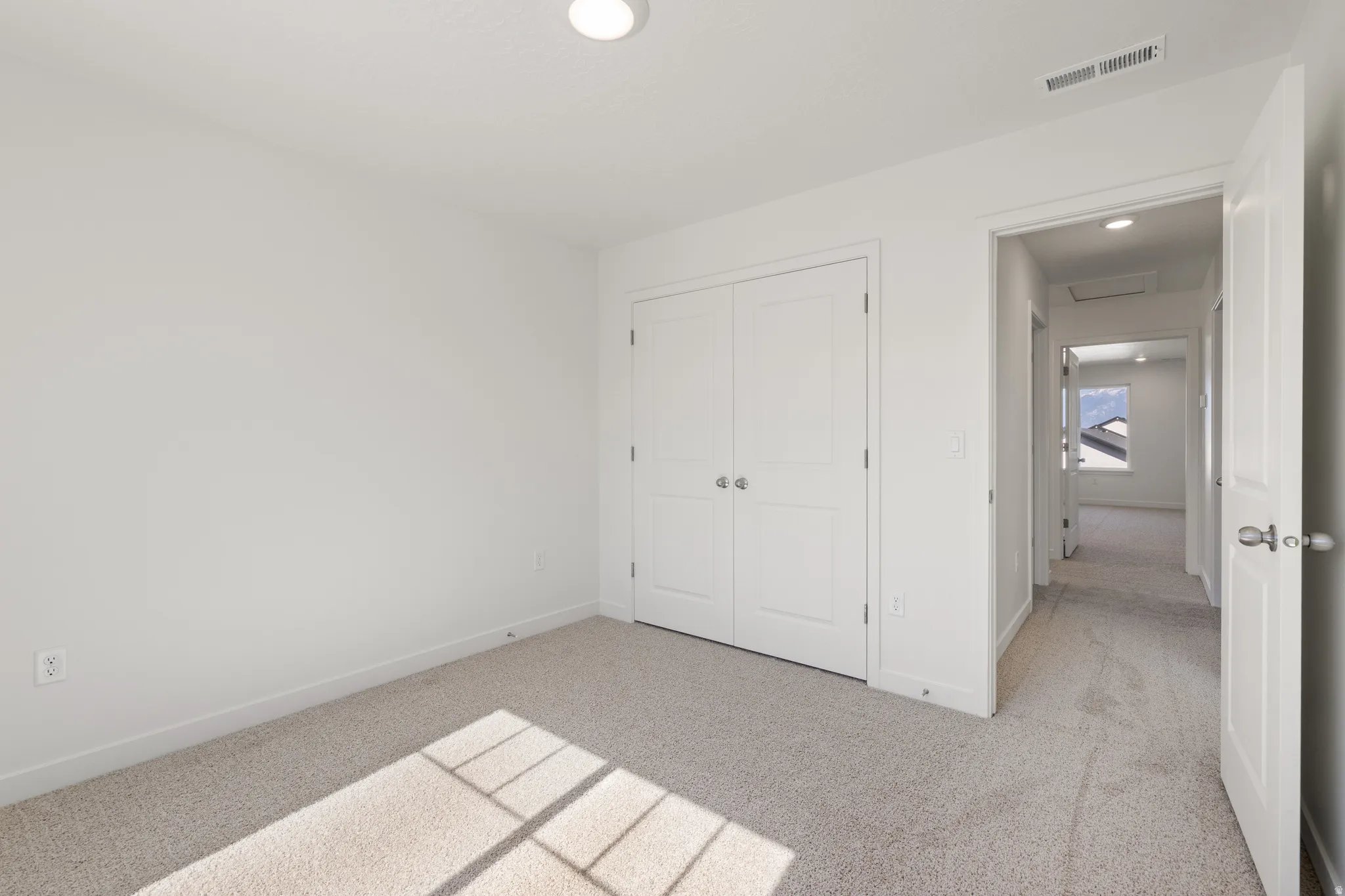 Bedroom featuring light-colored carpet flooring and a double-door closet