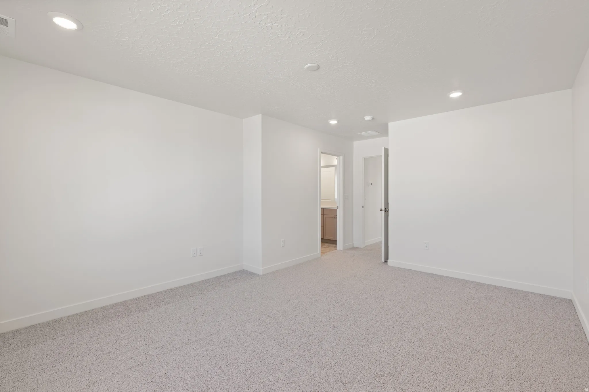 Spacious room featuring light gray carpeting and white walls