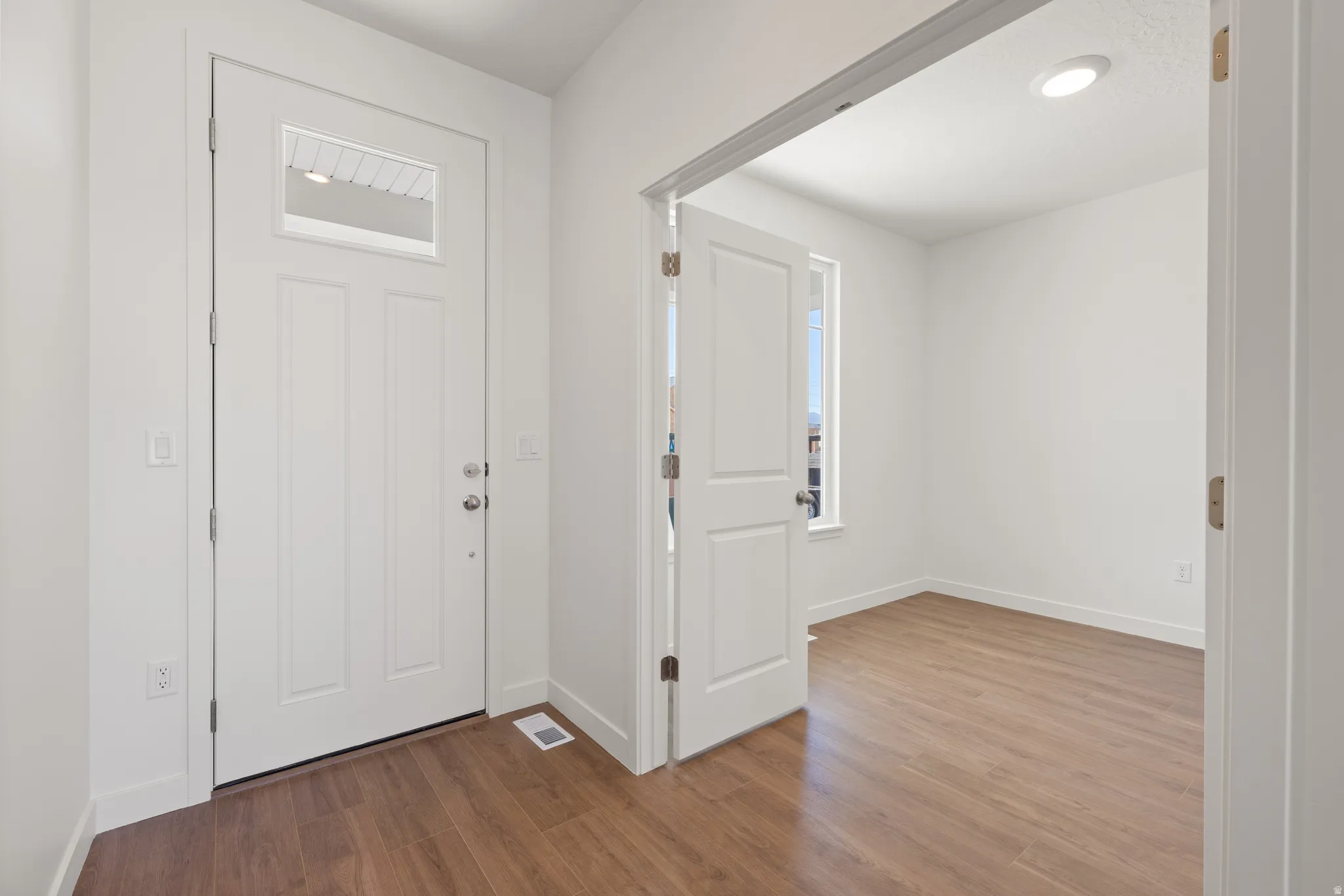 Entryway with wood-finish flooring, a white paneled door with an upper window, and recessed ceiling lighting