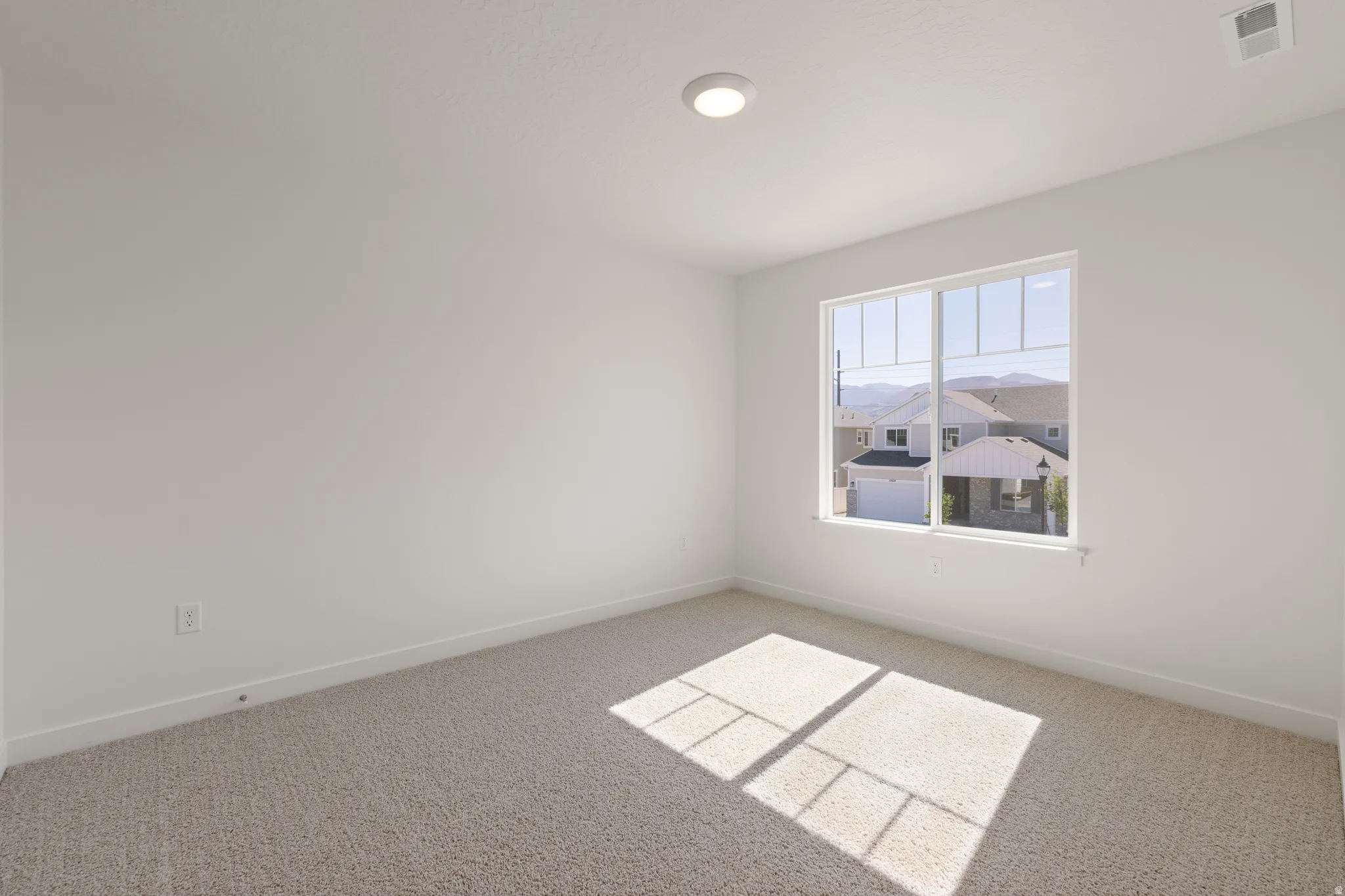 Carpeted room with white walls, a single window, and a flush-mount ceiling light