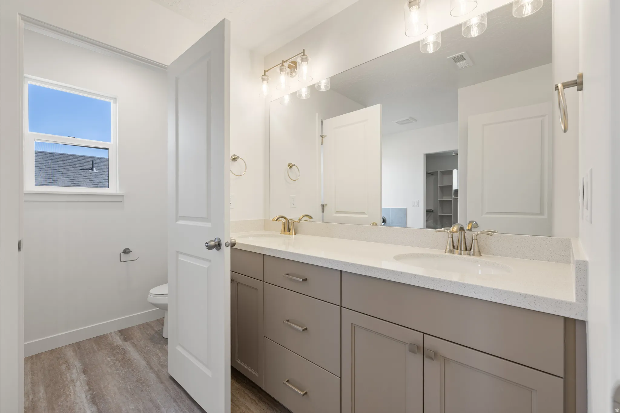 Double vanity with light gray cabinetry, integrated sinks, brushed nickel faucets, and a large wall-mounted mirror