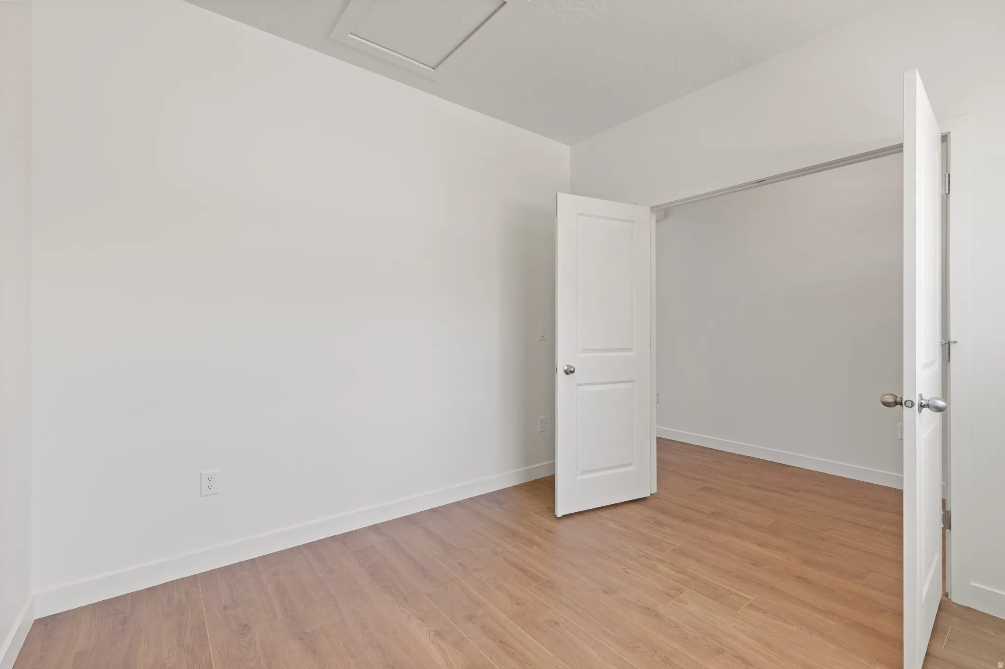 Spacious room featuring wood-finish flooring, white walls, and bright white trim