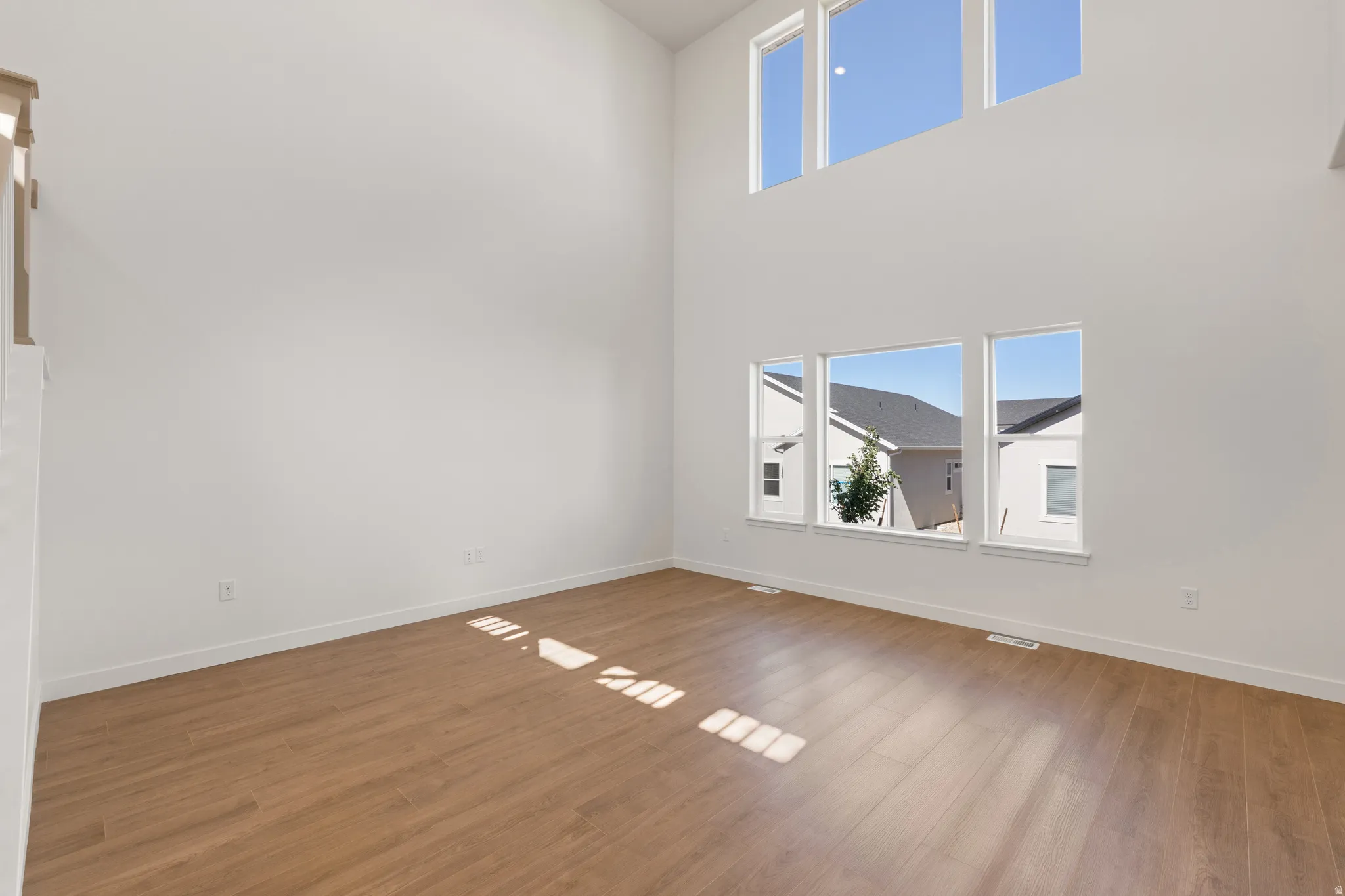 Spacious room featuring soaring ceilings and light wood-finish flooring