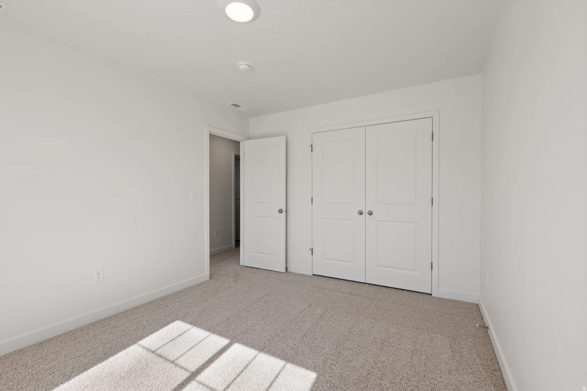 Neutral-toned carpeting paired with white walls, baseboards, and trim