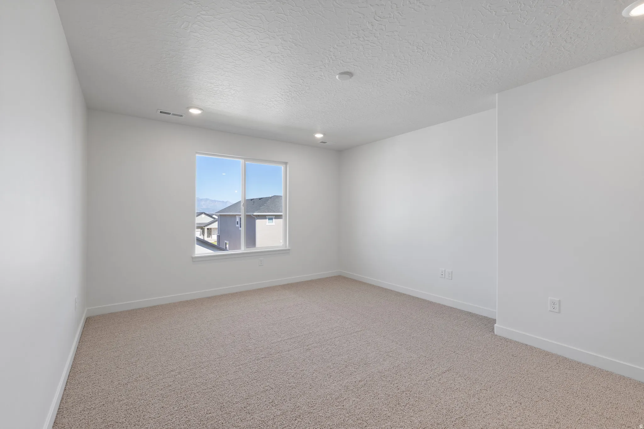 Bright room featuring light-toned carpeting and white walls