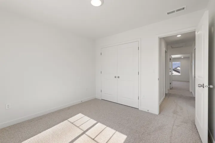 Bedroom featuring light-colored carpet flooring and a double-door closet