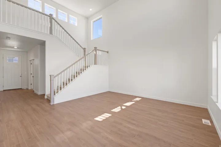 Two-story foyer featuring wood-finish flooring, a contemporary staircase with white balusters and light wood-tone handrails, and high ceilings