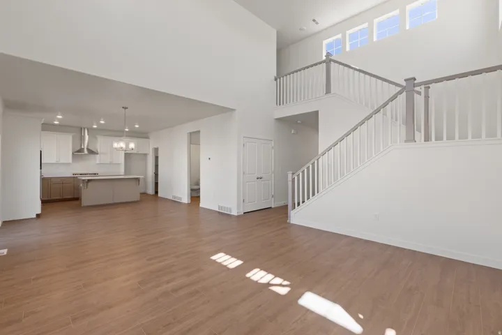 Open-concept living space featuring wood-finish flooring, a contemporary kitchen, and a double-height ceiling